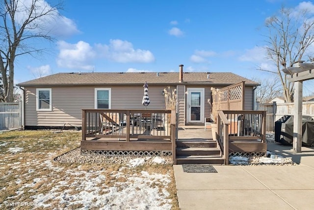 snow covered property with a wooden deck and a patio