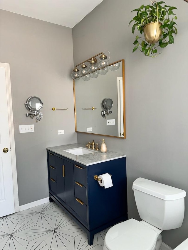 half bathroom with baseboards, vanity, and toilet