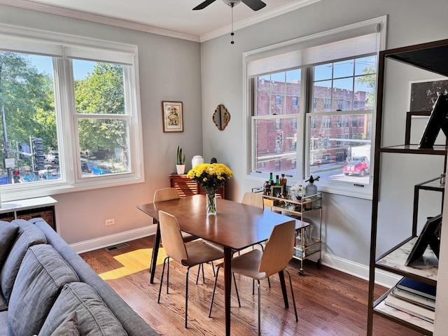 dining room featuring baseboards, visible vents, a ceiling fan, ornamental molding, and wood finished floors