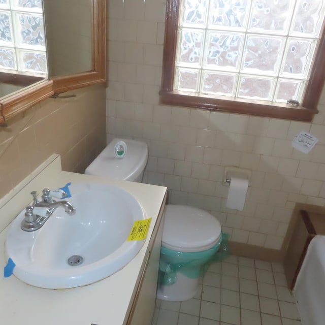 bathroom with toilet, vanity, tile walls, and tile patterned floors