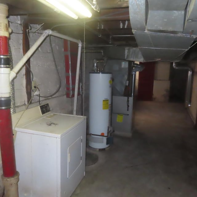 utility room with water heater, heating unit, and washer / dryer