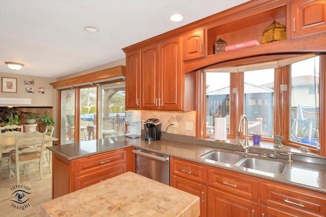 kitchen featuring stainless steel dishwasher, tasteful backsplash, light stone counters, and sink