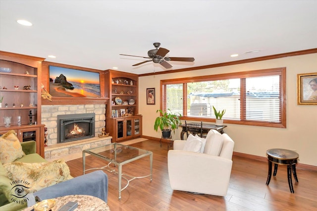 living room with ceiling fan, wood-type flooring, ornamental molding, and a fireplace