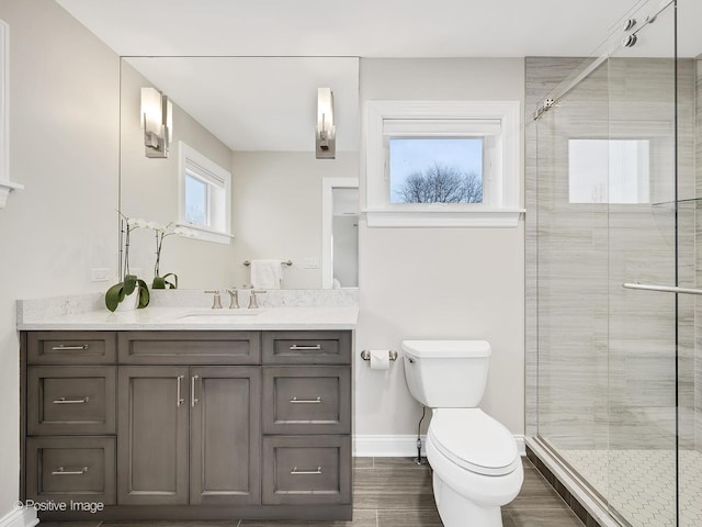 bathroom featuring toilet, a shower with shower door, and vanity