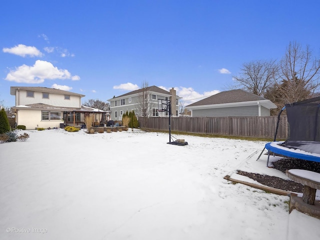 yard layered in snow with a trampoline