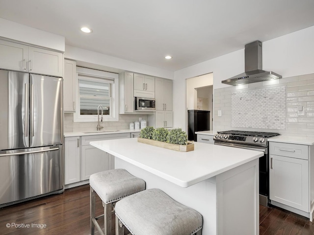 kitchen with appliances with stainless steel finishes, wall chimney exhaust hood, sink, a kitchen island, and decorative backsplash