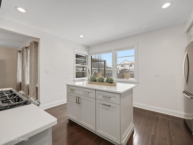 kitchen with white cabinets, a center island, stainless steel refrigerator, and dark wood-type flooring