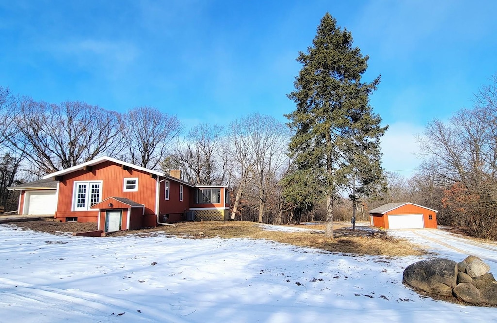 view of snow covered exterior with a garage and an outdoor structure