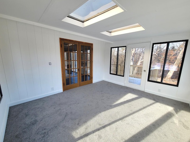 empty room featuring a skylight, dark carpet, and french doors