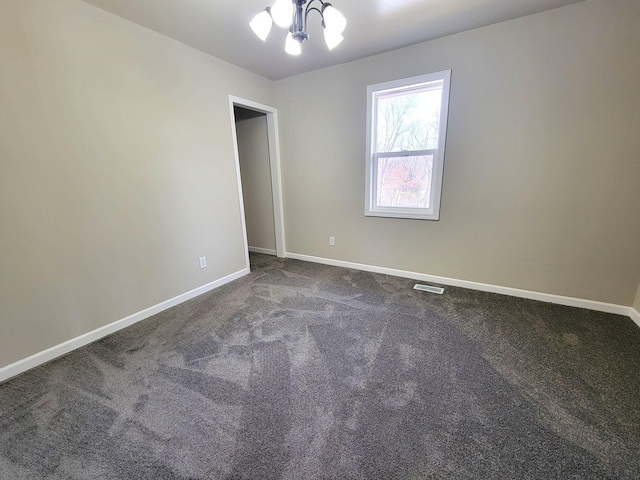 spare room with a notable chandelier and carpet flooring