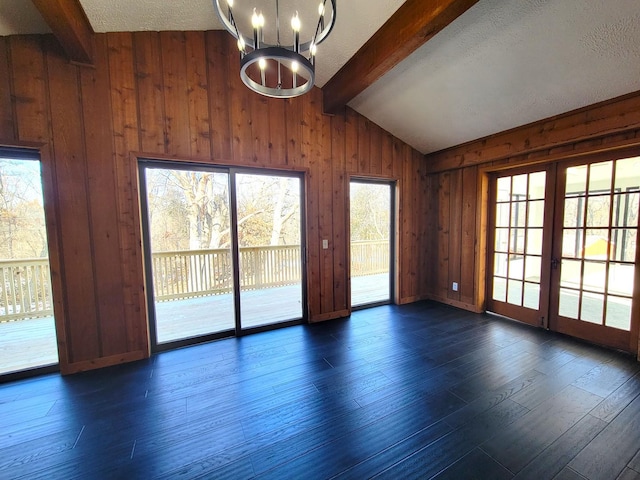 spare room featuring wood walls, dark hardwood / wood-style floors, lofted ceiling with beams, and a notable chandelier