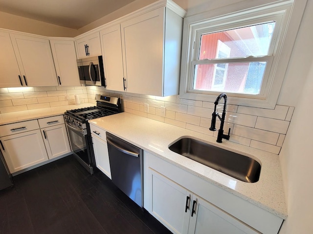 kitchen with sink, white cabinetry, stainless steel appliances, and tasteful backsplash