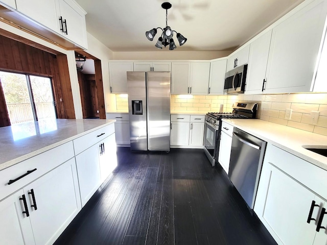 kitchen featuring white cabinets, dark hardwood / wood-style flooring, stainless steel appliances, backsplash, and hanging light fixtures