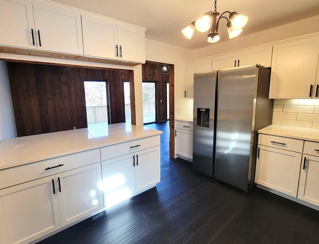 kitchen featuring white cabinetry, decorative backsplash, stainless steel fridge, and hanging light fixtures