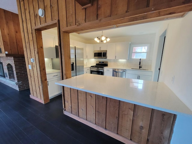 kitchen featuring white cabinetry, wood walls, stainless steel appliances, dark hardwood / wood-style flooring, and sink