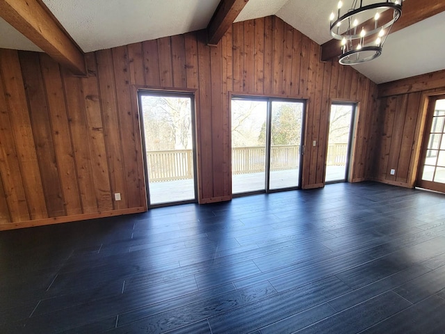 unfurnished room featuring dark hardwood / wood-style floors, wood walls, lofted ceiling with beams, and a notable chandelier