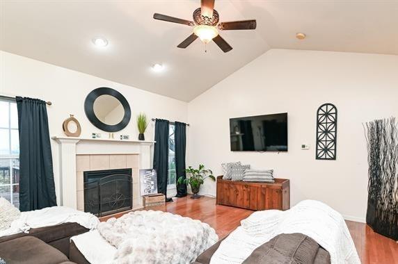 521 E 2700 N Rd, Deland, IL 61839 - living room with a tile fireplace, light hardwood / wood-style floors, vaulted ceiling, and ceiling fan