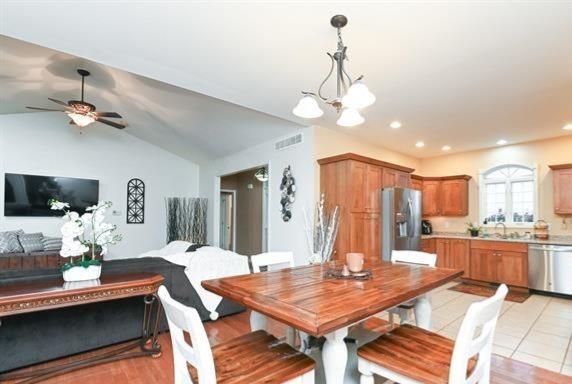 521 E 2700 N Rd, Deland, IL 61839 - dining room with ceiling fan with notable chandelier, sink, lofted ceiling, and light tile patterned flooring