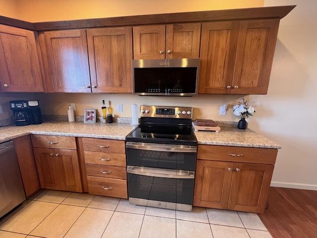 521 E 2700 N Rd, Deland, IL 61839 - kitchen with light tile patterned floors, light stone countertops, and appliances with stainless steel finishes