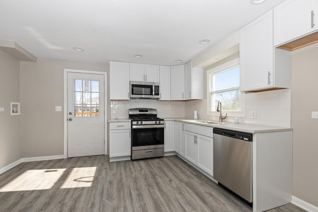 kitchen with a wealth of natural light, sink, white cabinetry, light wood-type flooring, and appliances with stainless steel finishes