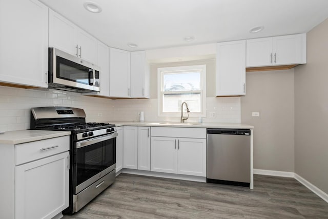 kitchen with backsplash, sink, white cabinetry, light hardwood / wood-style flooring, and stainless steel appliances