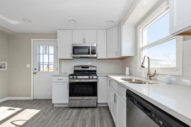 kitchen with appliances with stainless steel finishes, light hardwood / wood-style floors, white cabinets, and sink