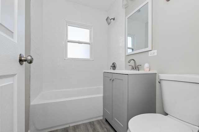 full bathroom featuring hardwood / wood-style floors, toilet, vanity, and tiled shower / bath combo