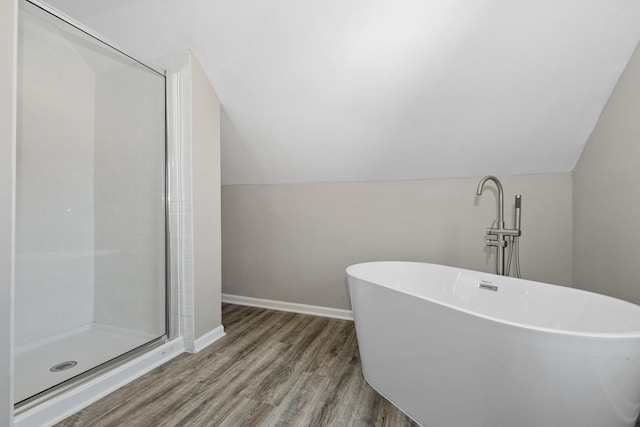 bathroom with vaulted ceiling, hardwood / wood-style floors, and plus walk in shower