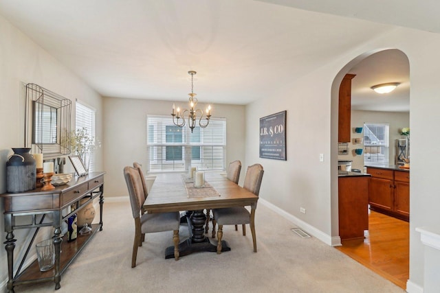 dining space featuring a chandelier and light carpet