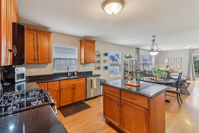 kitchen featuring a kitchen island, pendant lighting, dishwasher, sink, and light hardwood / wood-style flooring