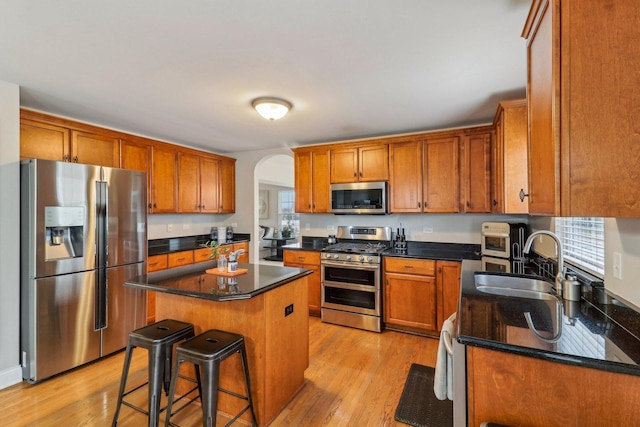 kitchen with sink, a breakfast bar area, a center island, stainless steel appliances, and light hardwood / wood-style floors