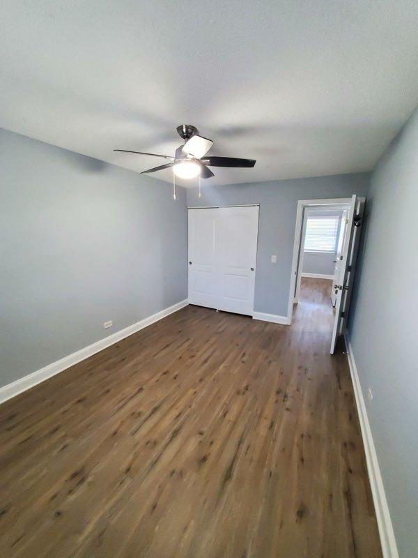 unfurnished bedroom with ceiling fan and dark hardwood / wood-style flooring