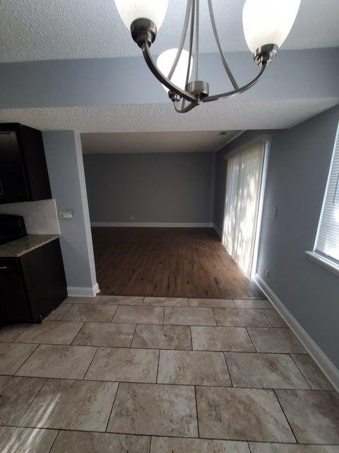 unfurnished dining area with a wealth of natural light, tile patterned floors, and a textured ceiling