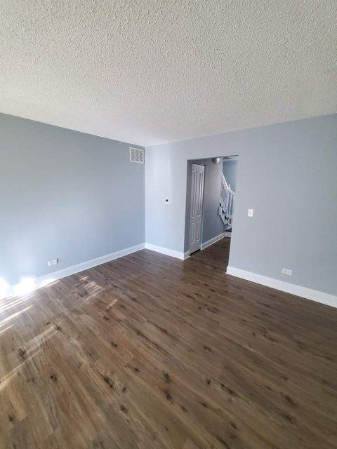 spare room with a textured ceiling and dark hardwood / wood-style flooring