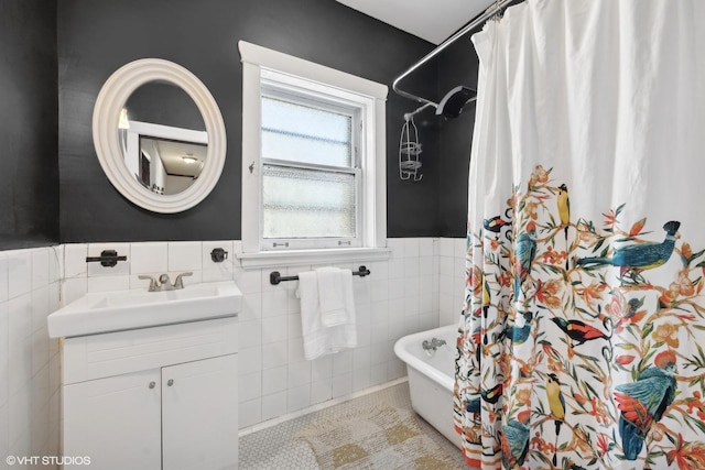 full bathroom featuring a wainscoted wall, a shower with shower curtain, tile walls, vanity, and a tub