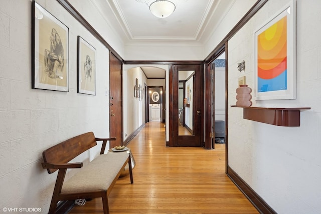 hall featuring light wood-type flooring, arched walkways, and crown molding