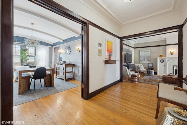 corridor featuring lofted ceiling, ornamental molding, a chandelier, light wood-type flooring, and baseboards