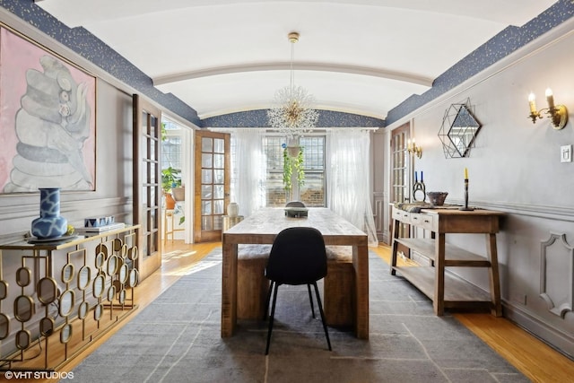 dining space featuring wood finished floors, baseboards, vaulted ceiling, french doors, and an inviting chandelier