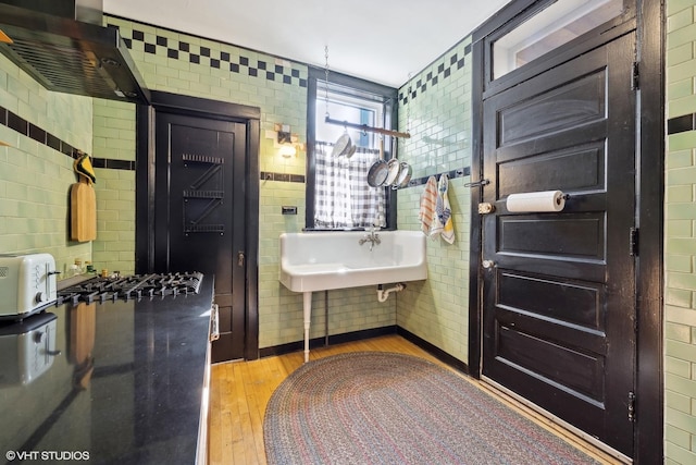 bathroom featuring wood finished floors, a sink, and tile walls