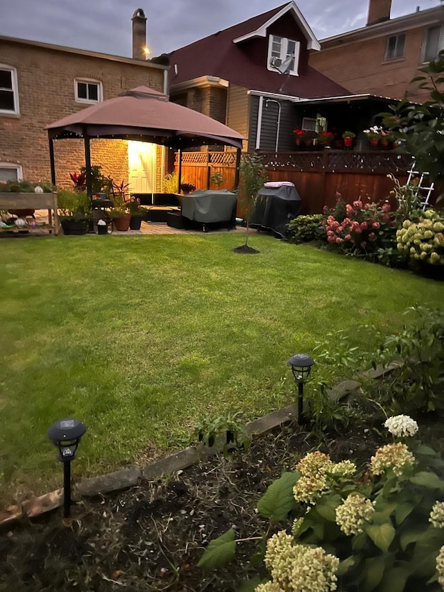 back house at dusk featuring a gazebo and a yard