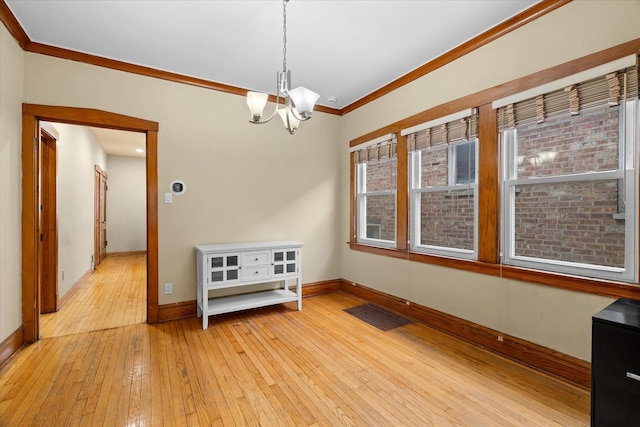 interior space with an inviting chandelier, ornamental molding, and light hardwood / wood-style flooring