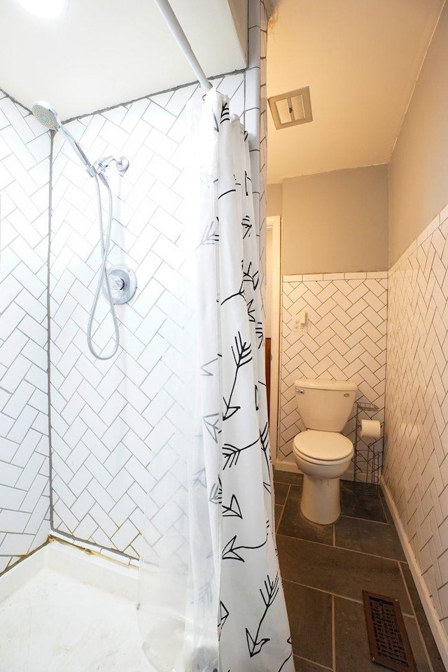 bathroom with toilet, tile walls, and curtained shower