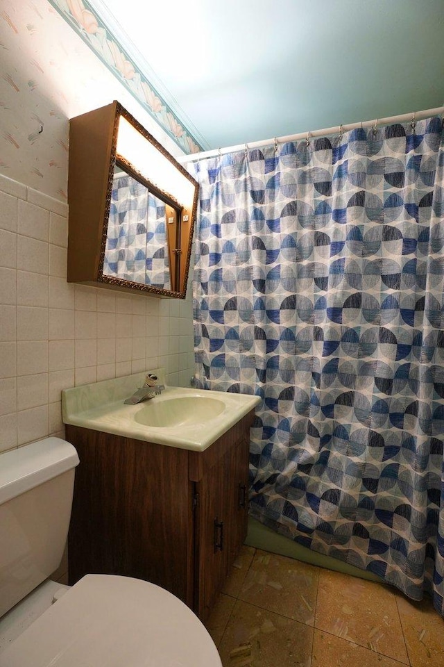 bathroom with toilet, tile walls, tile patterned floors, and vanity