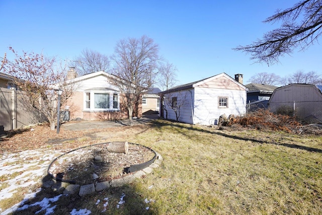 back of house with a storage shed and a lawn