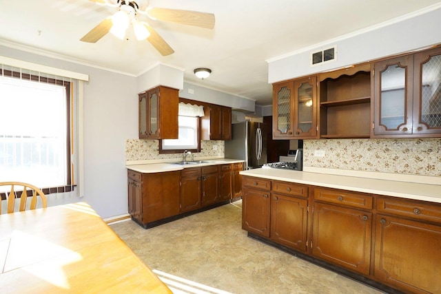 kitchen with ceiling fan, decorative backsplash, stainless steel refrigerator, crown molding, and sink