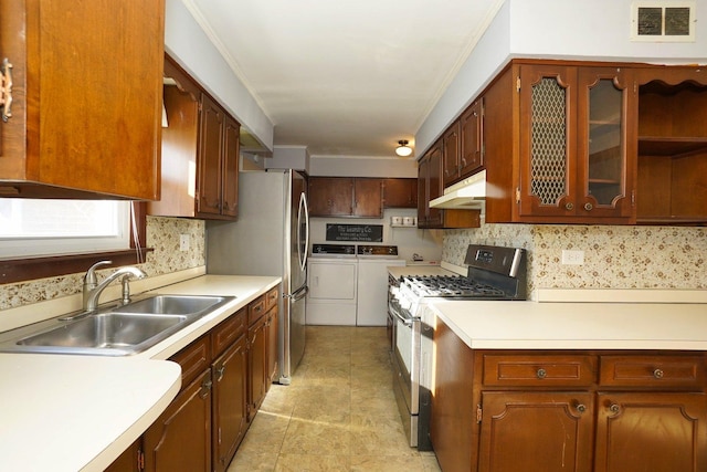 kitchen with decorative backsplash, sink, washing machine and clothes dryer, and stainless steel gas range oven