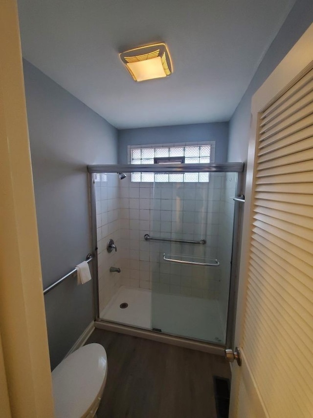 bathroom with walk in shower, toilet, and hardwood / wood-style flooring