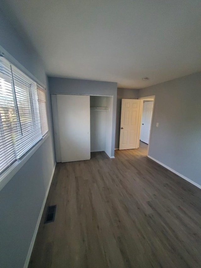 unfurnished bedroom with a closet and dark hardwood / wood-style floors