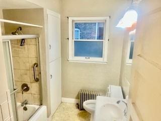 bathroom featuring toilet, radiator, and combined bath / shower with glass door