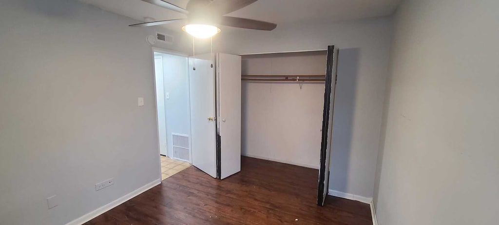 unfurnished bedroom featuring ceiling fan, a closet, and dark hardwood / wood-style flooring